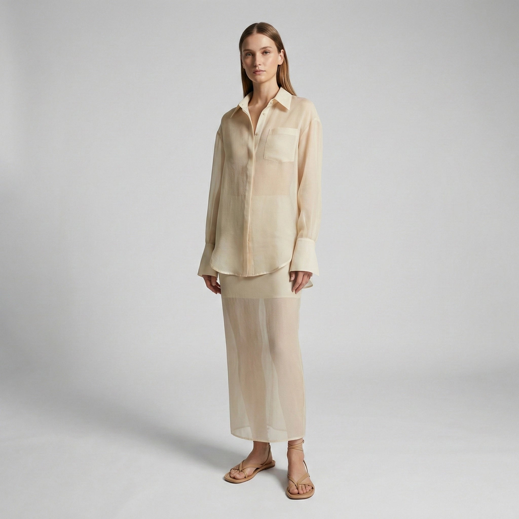 Woman wearing a beige shirt and pants on a plain background