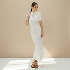 Woman wearing a white ribbed dress on a gray background