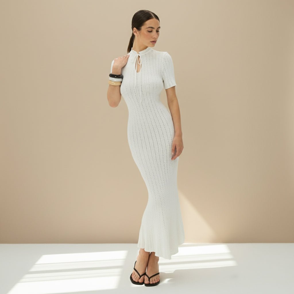 Woman wearing a white ribbed dress on a gray background