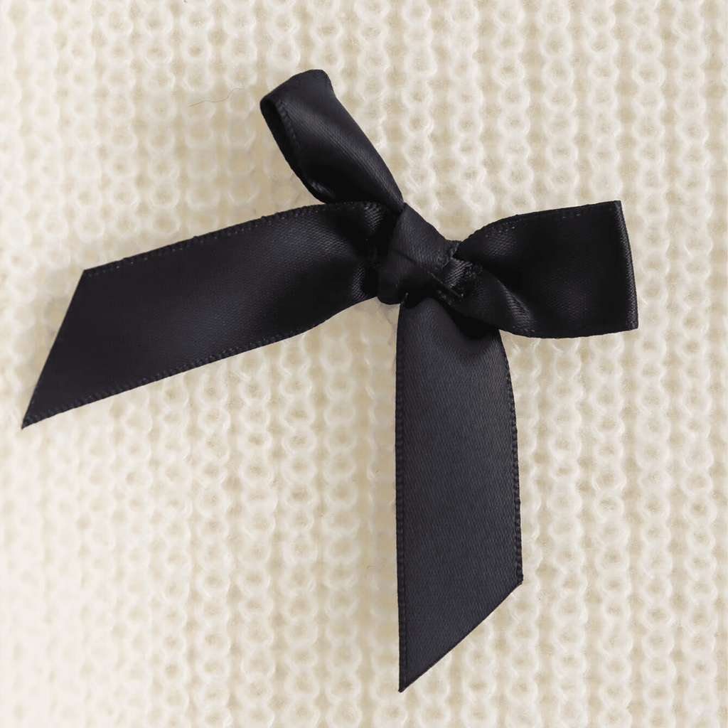 Black satin ribbon bow on a textured beige background