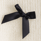 Black satin ribbon bow on a textured beige background