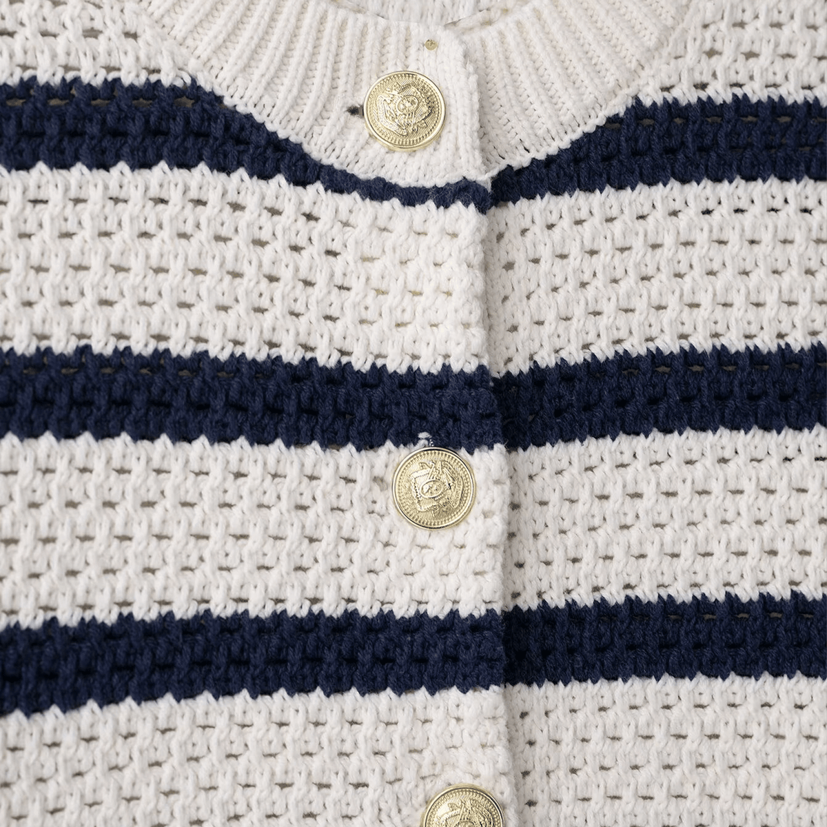 Close-up of a white and navy striped garment with gold buttons.