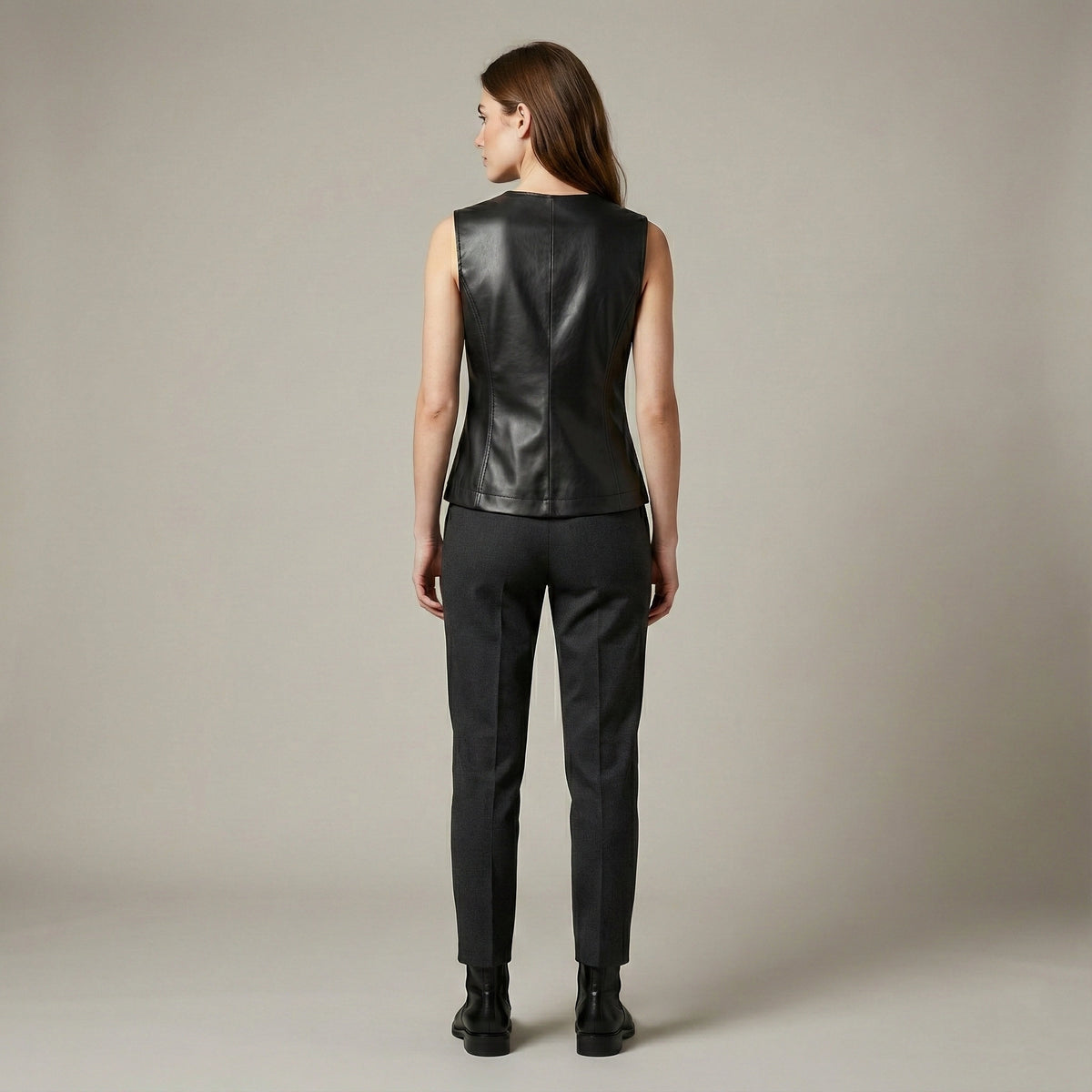Person wearing a black leather vest and pants on a neutral background