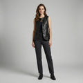 Woman wearing a black leather vest and pants on a gray background