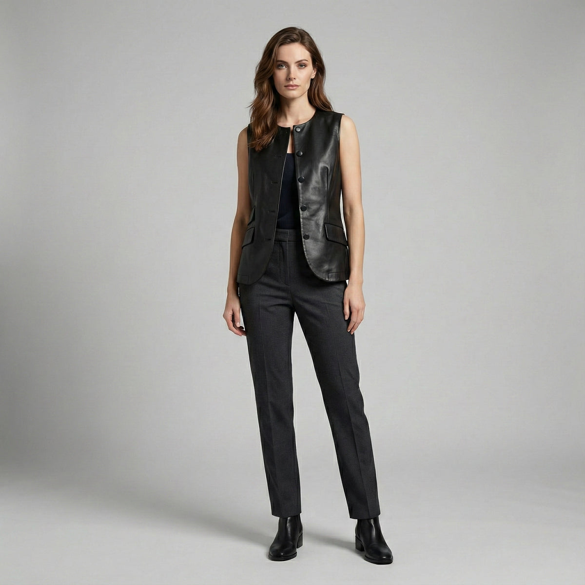 Woman wearing a black leather vest and pants on a gray background