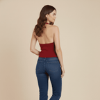 Woman wearing a red top and blue jeans on a beige background