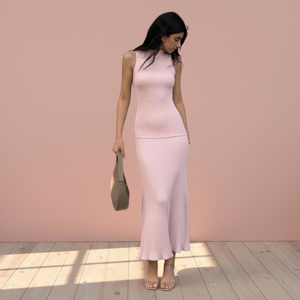 Woman wearing a pink ribbed dress holding a beige handbag on a light gray background
