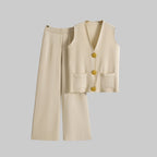 Beige vest and wide-leg pants on hangers against a gray background