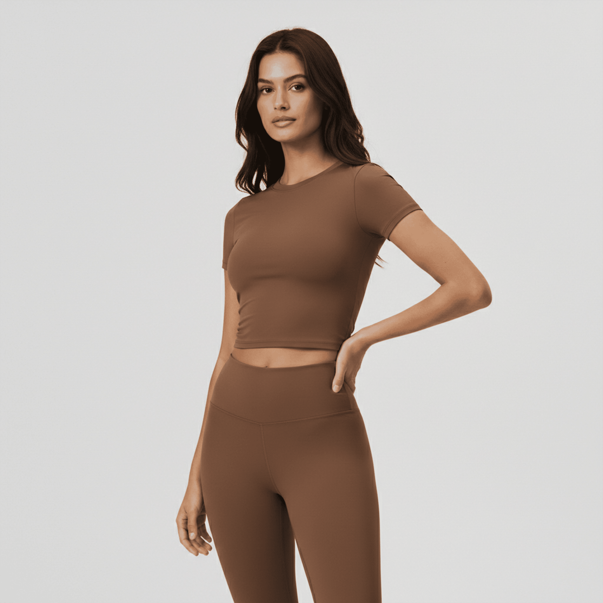 Woman wearing a brown athletic outfit on a light gray background