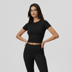Woman wearing a black crop top and leggings on a light gray background