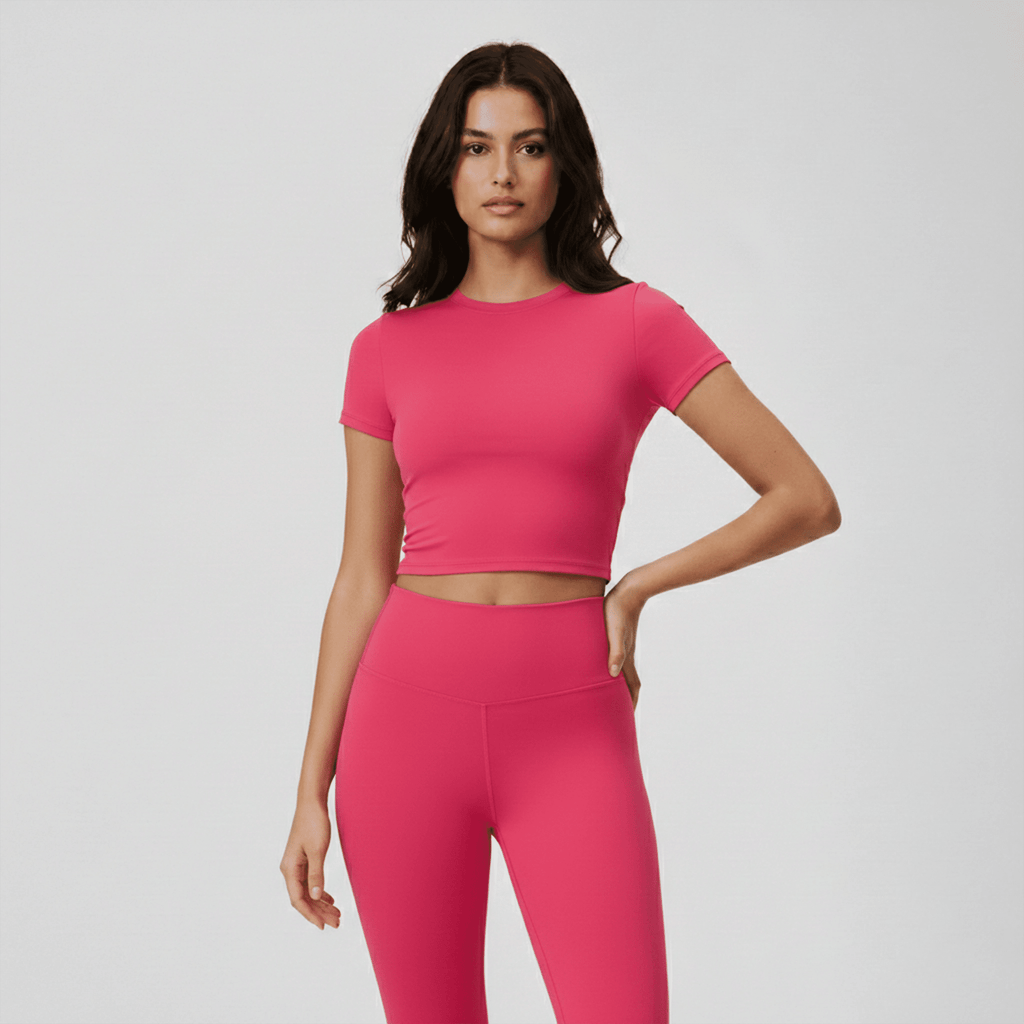 Woman wearing a bright pink athletic outfit on a light gray background