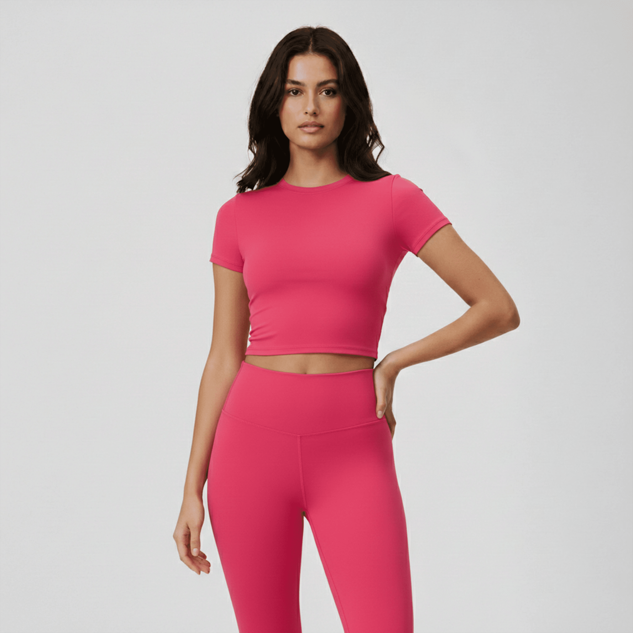 Woman wearing a bright pink athletic outfit on a light gray background