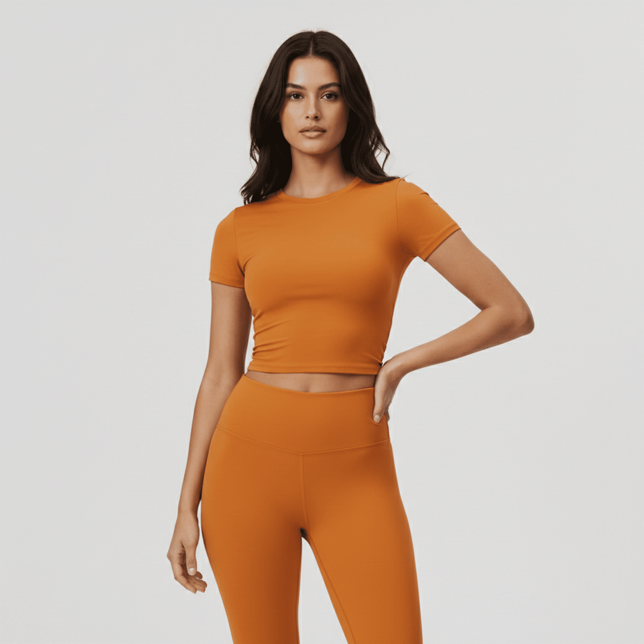 Woman wearing an orange athletic outfit on a plain background