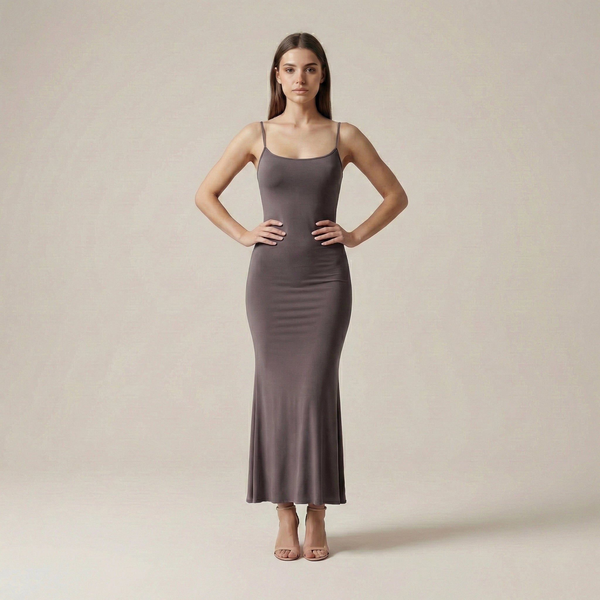 Woman wearing a long, fitted dress against a plain background