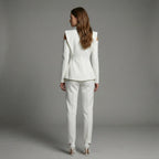 Woman wearing a white suit standing against a gray background