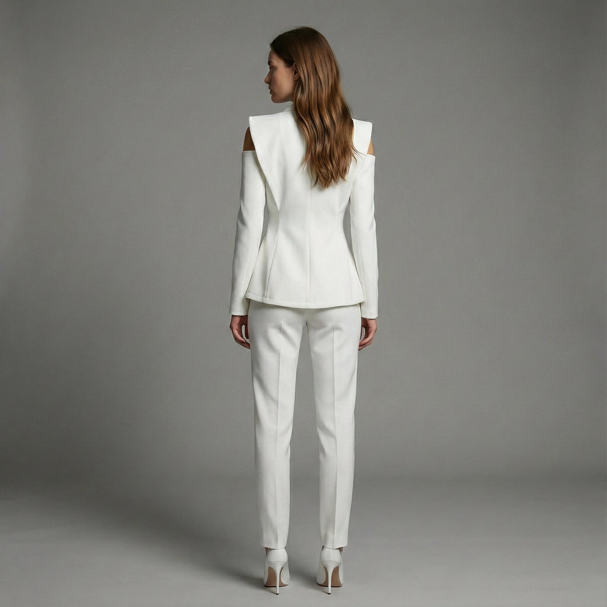 Woman wearing a white suit standing against a gray background