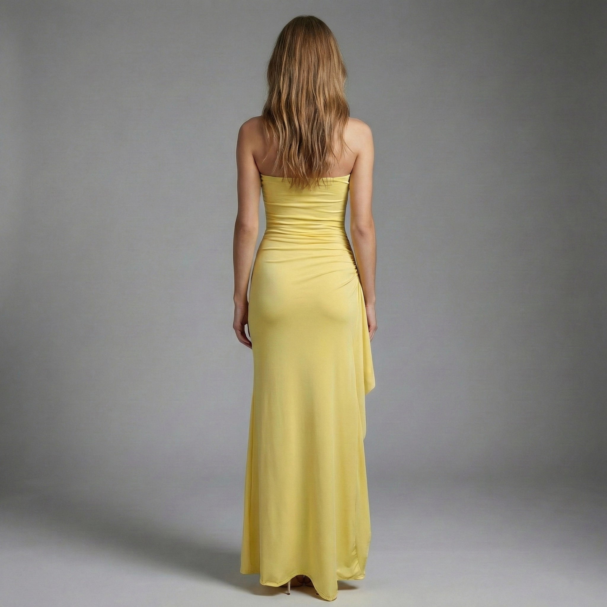 Woman wearing a yellow strapless gown against a gray background