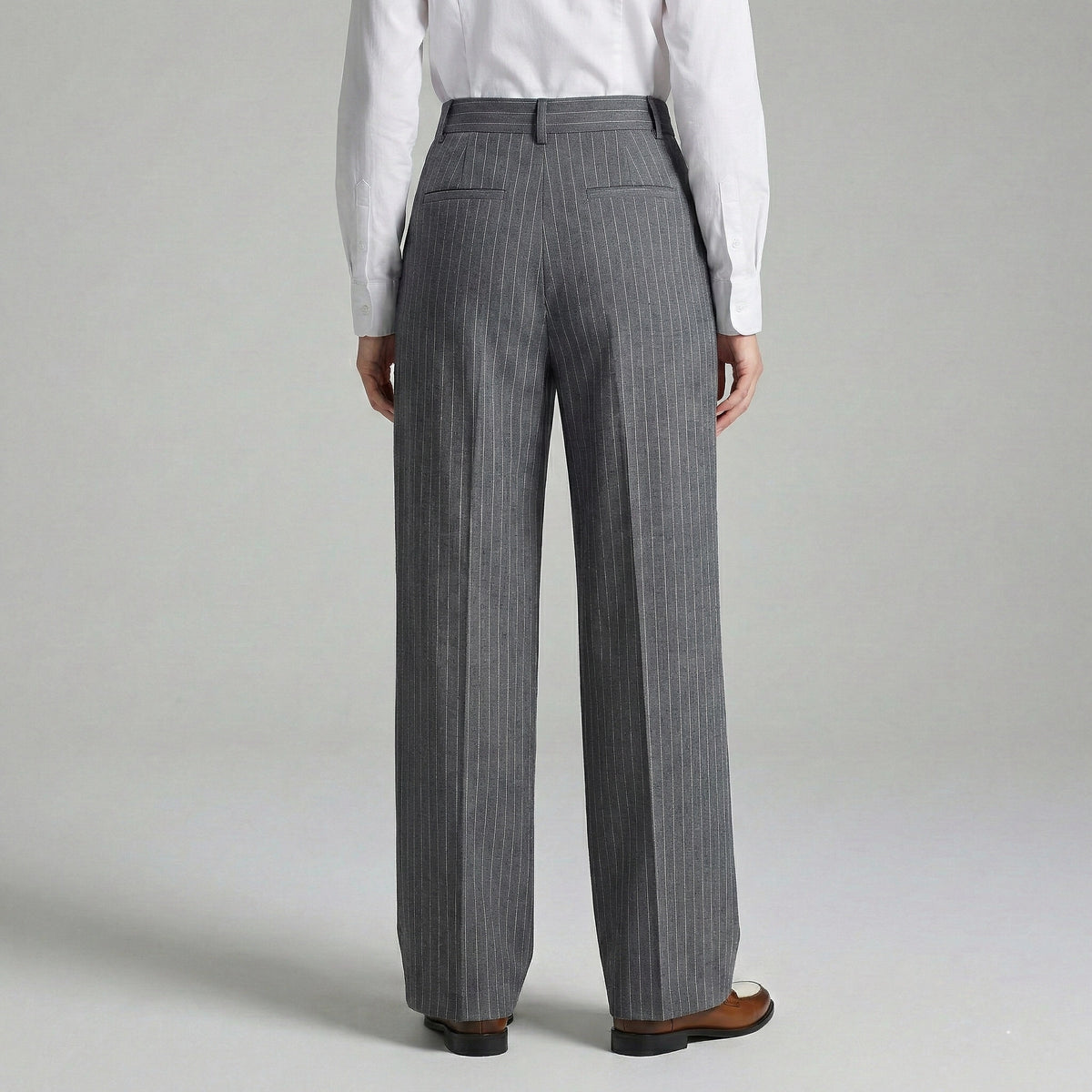 Person wearing gray pinstripe pants and a white shirt on a plain background