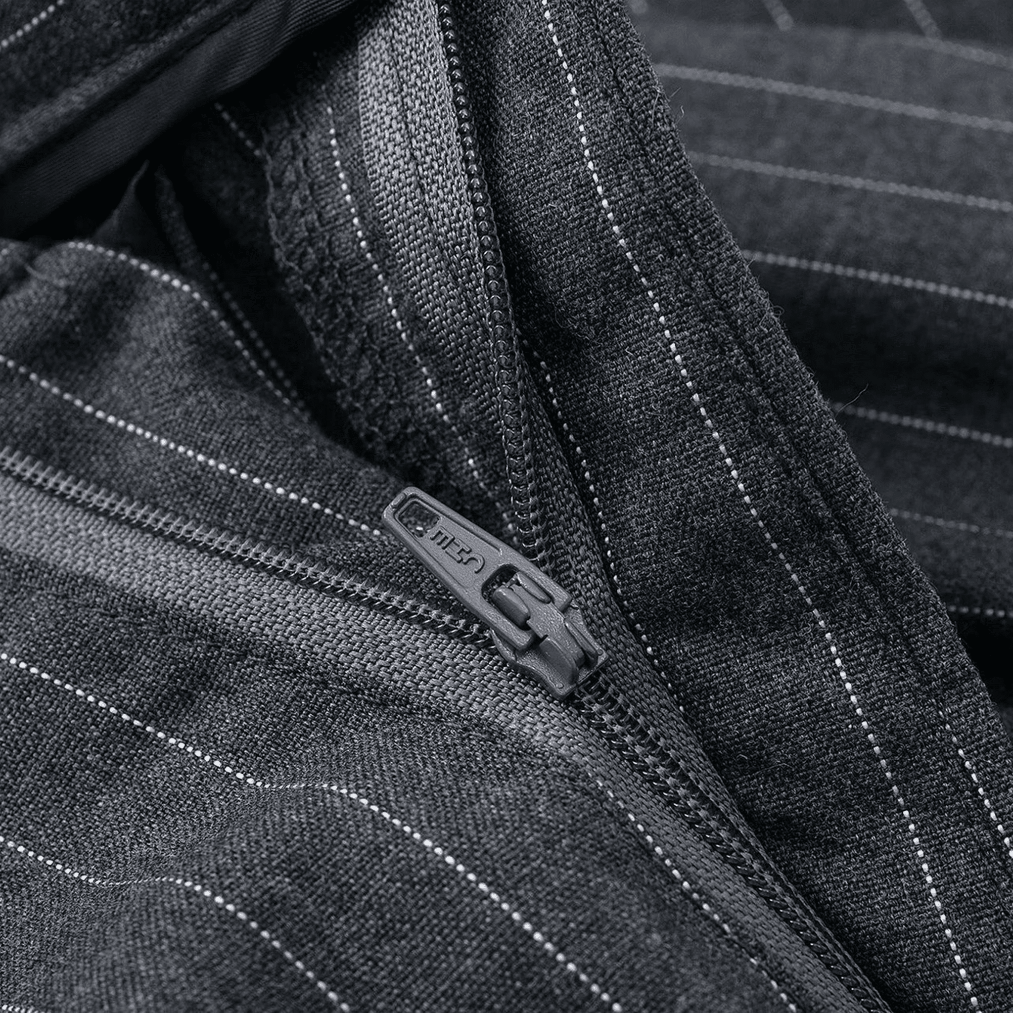 Close-up of a zipper on a dark fabric with a subtle pattern