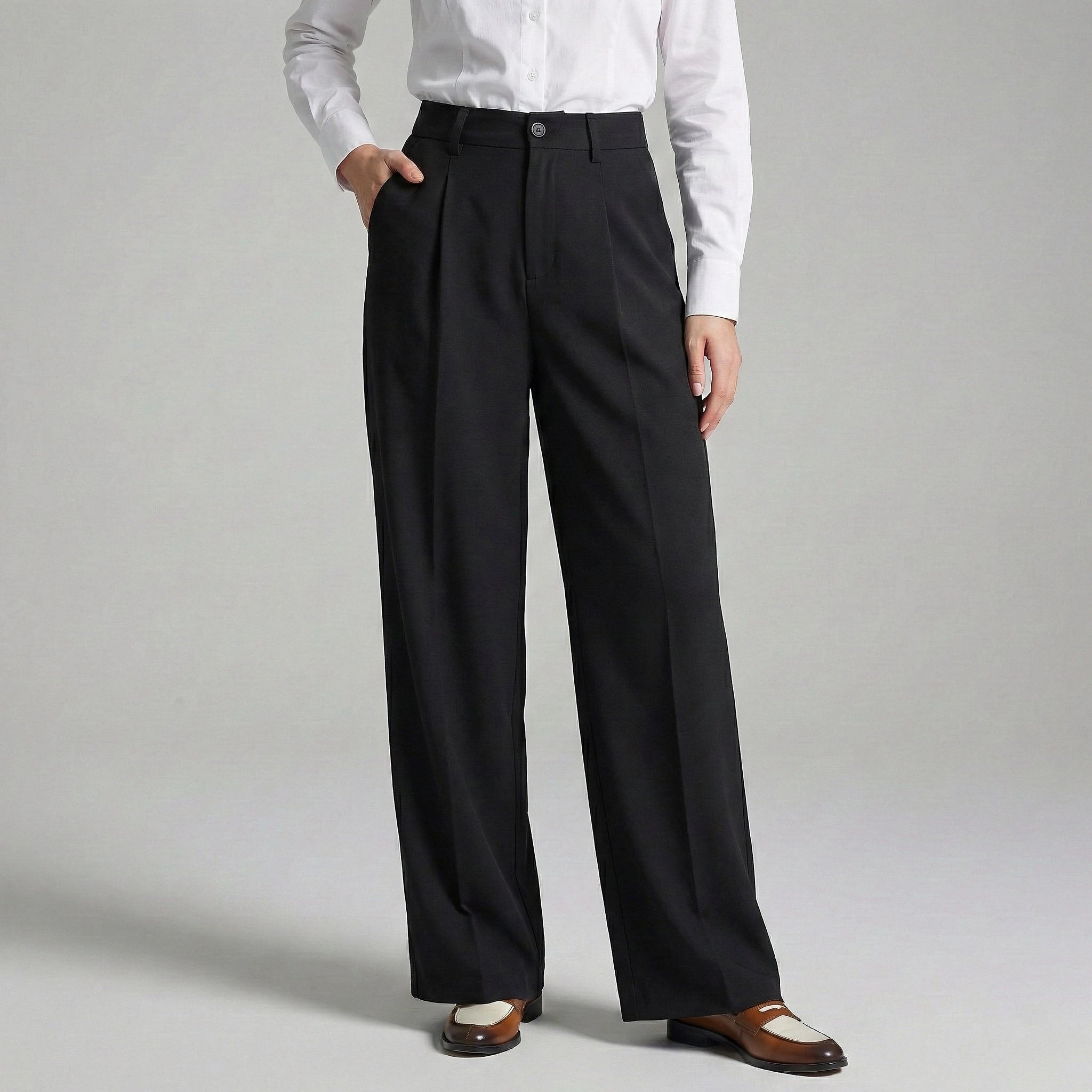 Person wearing black dress pants with a white shirt on a gray background