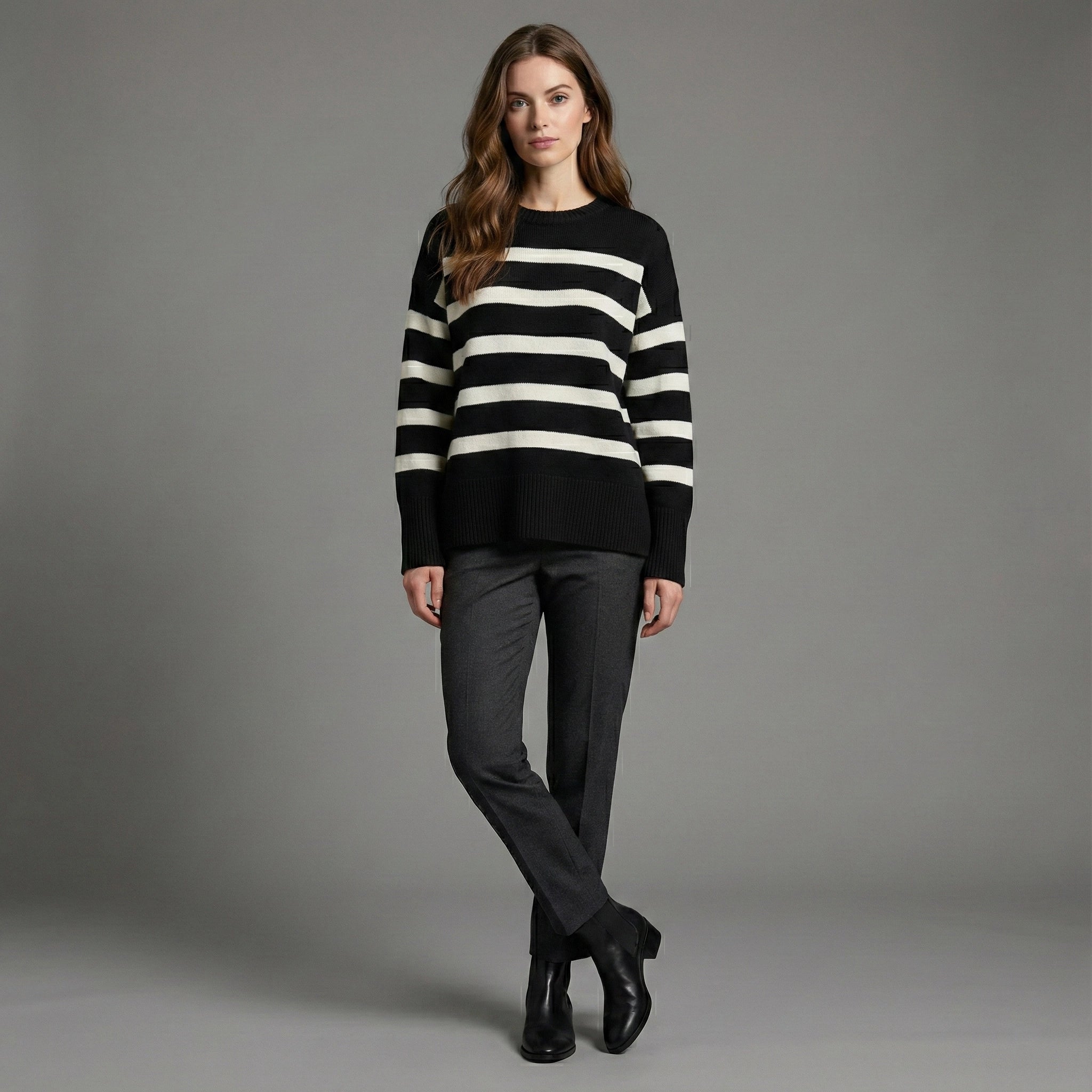 Woman wearing a black and white striped sweater with gray pants on a gray background