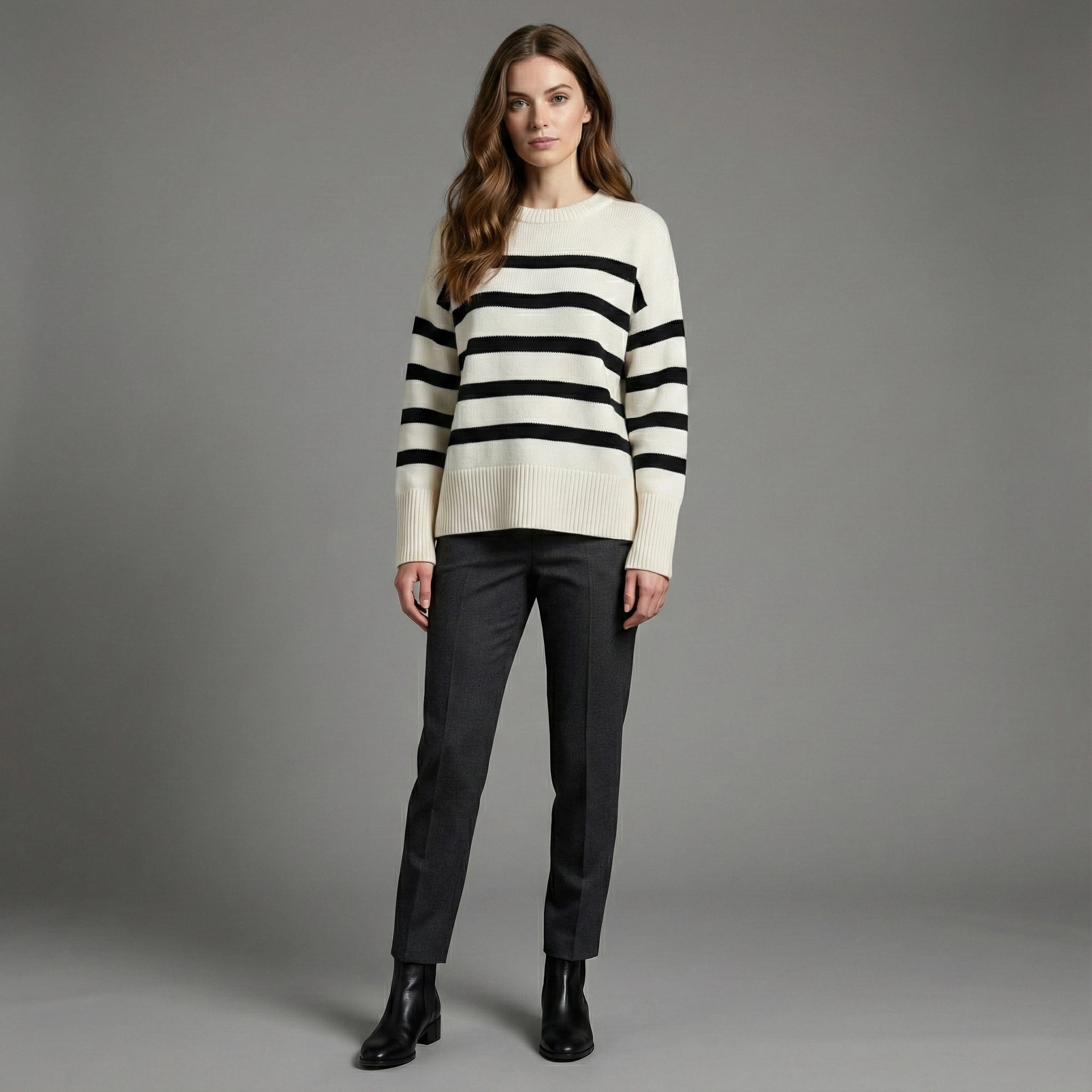 Woman wearing a striped sweater and black pants on a gray background