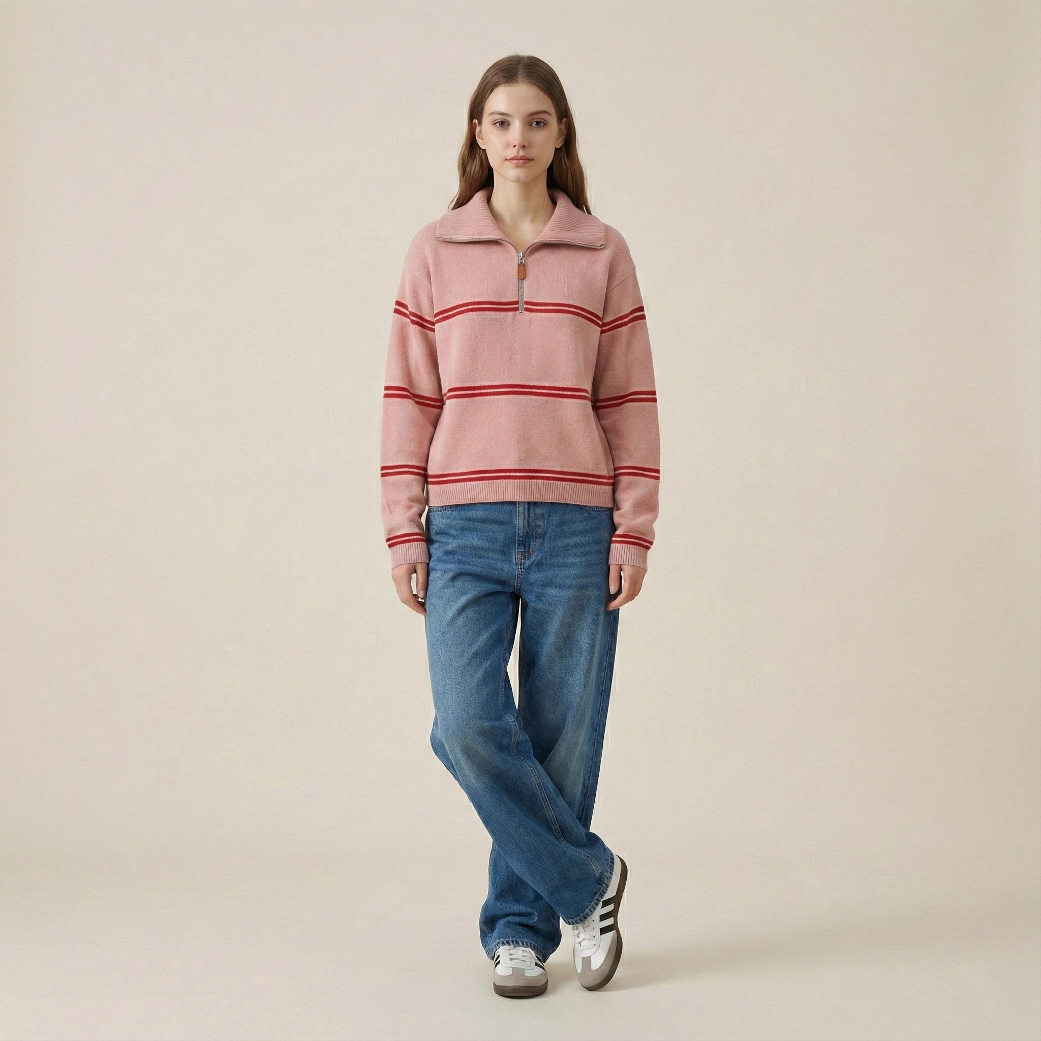 Person wearing a pink striped sweater and blue jeans on a beige background