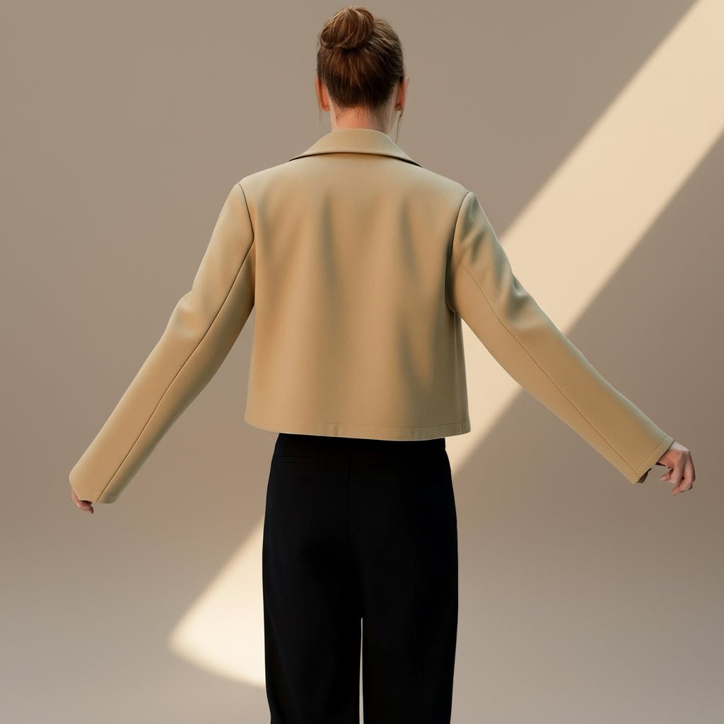 Person wearing a beige jacket and black pants against a neutral background