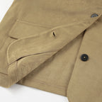 Close-up of a beige jacket with a button and pocket detail on a white background