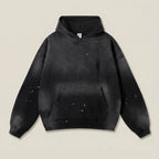 Black hoodie with splatter design on a beige background