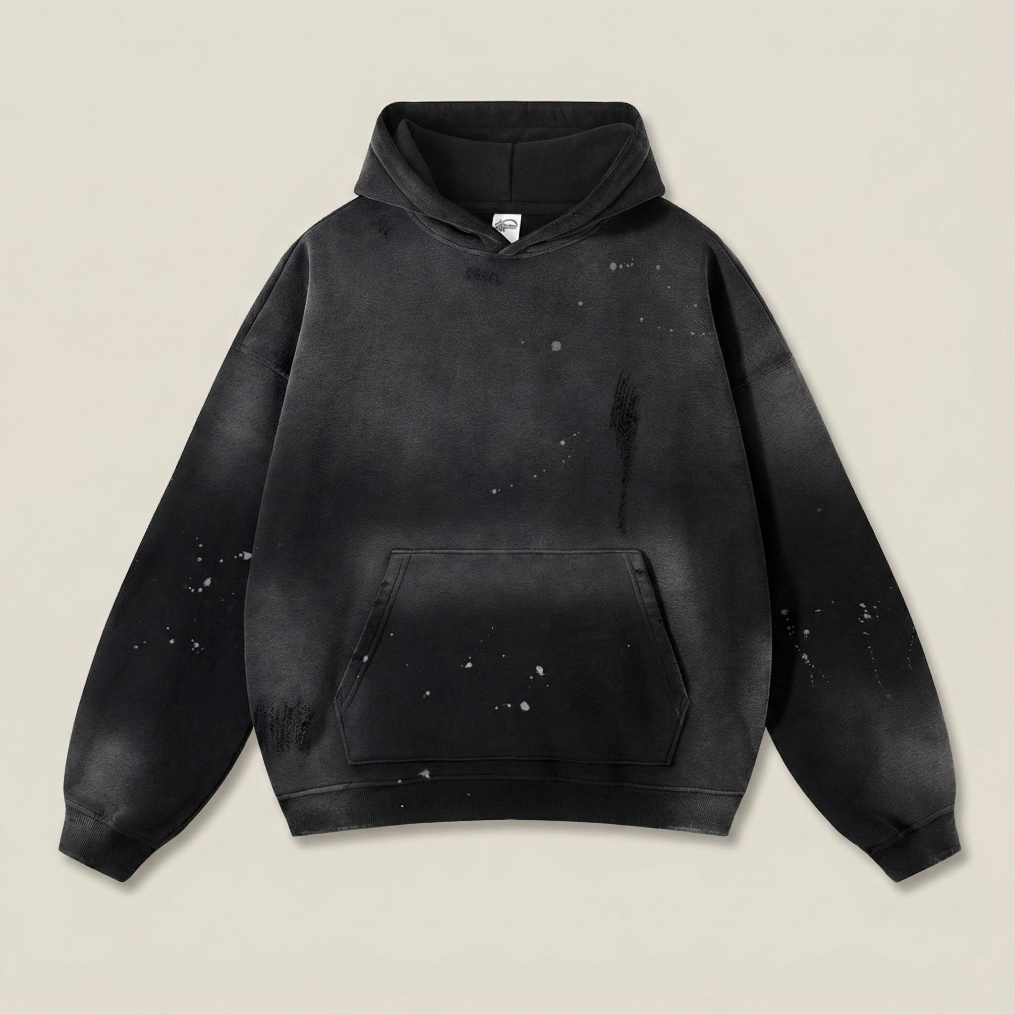Black hoodie with splatter design on a beige background