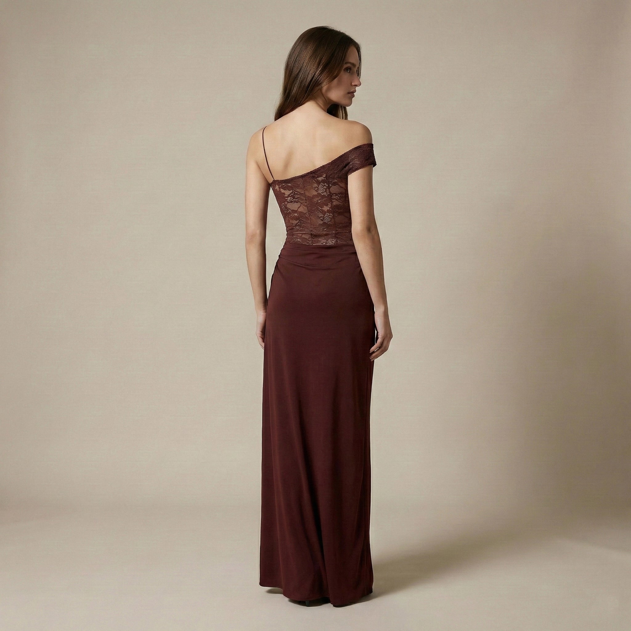 Woman wearing a burgundy one-shoulder gown against a beige background