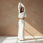 Person wearing a white oversized sweater and skirt on a light gray background