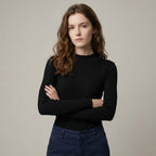 Woman wearing a black sweater and blue jeans against a plain background