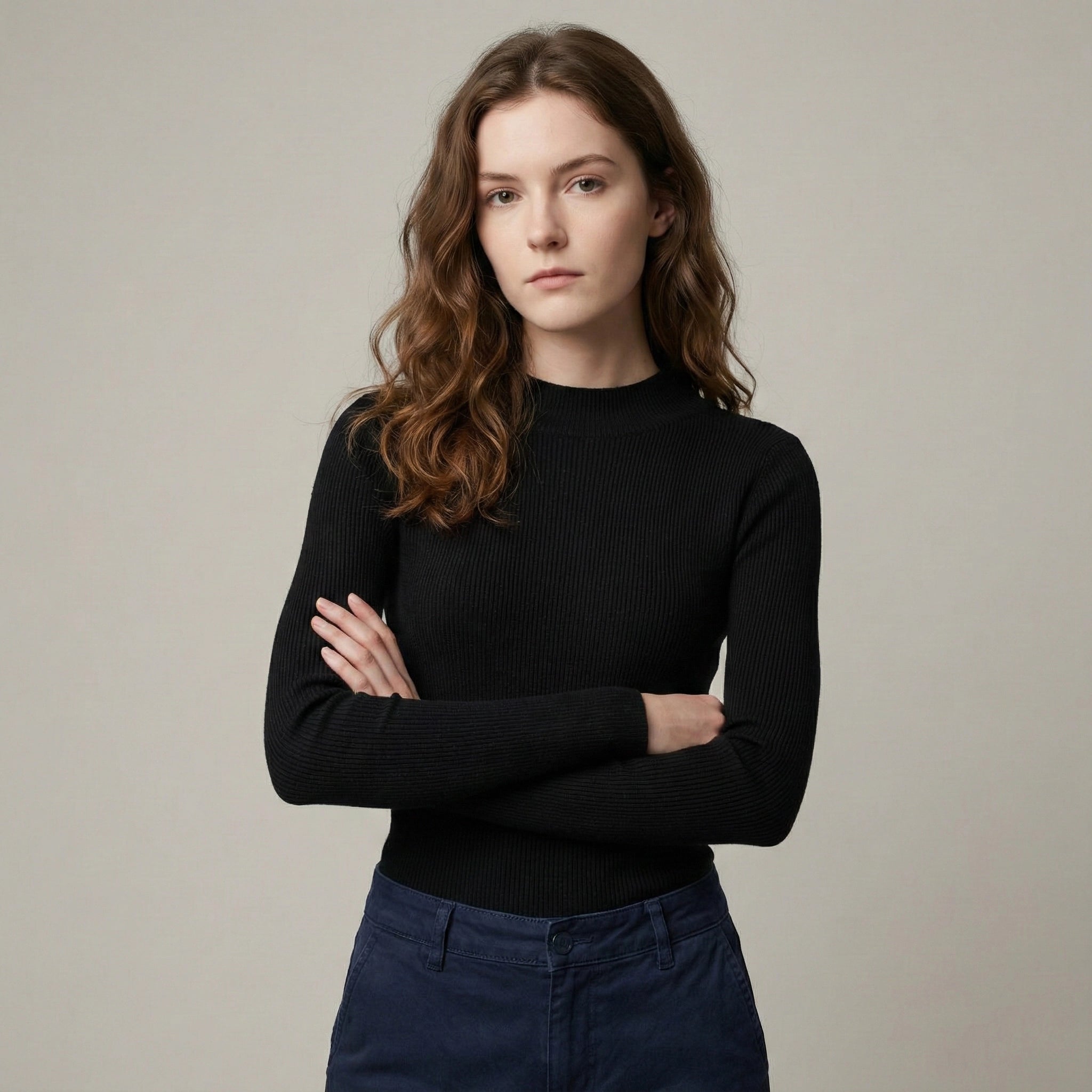 Woman wearing a black sweater and blue jeans against a plain background