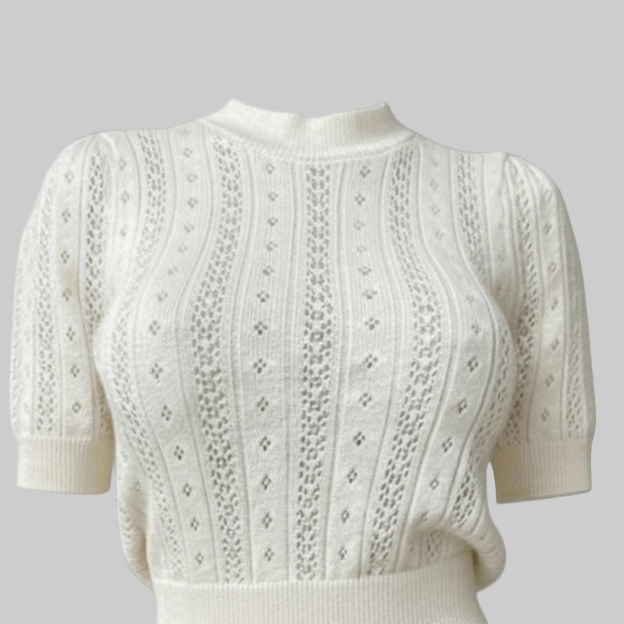 White knitted sweater with intricate patterns on a gray background