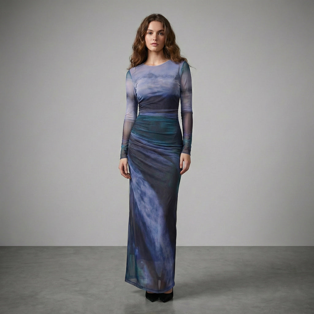Woman wearing a long, sheer dress with a gradient of blue and purple colors on a gray background.