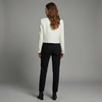 Woman wearing a white blazer and black pants against a gray background