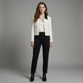 Woman wearing a white blazer and black pants against a gray background