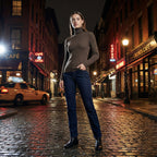 Woman standing on a city street at night with neon signs and a taxi in the background
