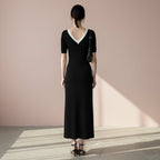 Woman wearing a black dress with a white collar on a gray background