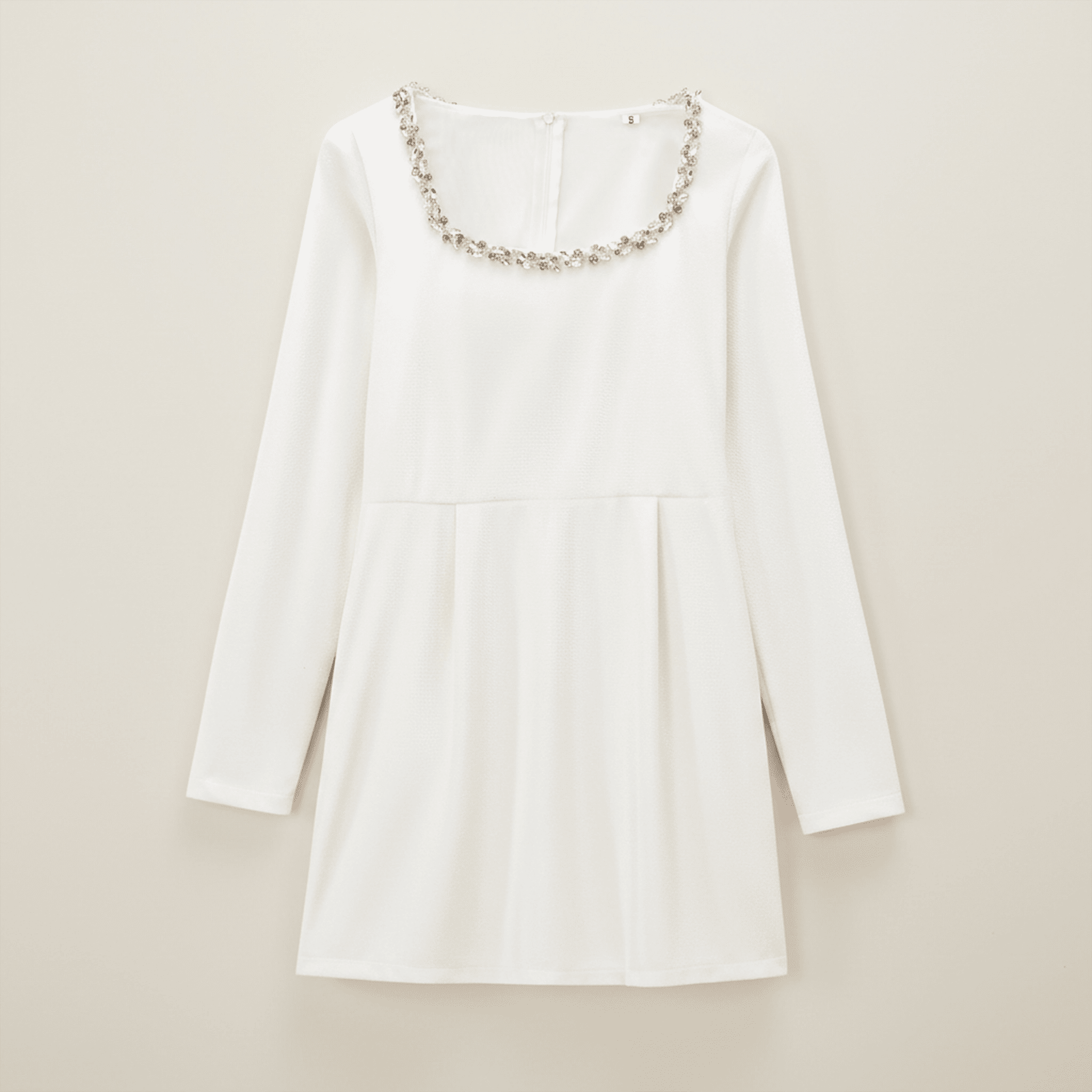 White dress with decorative neckline on a beige background