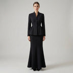 Woman wearing a black suit on a plain background