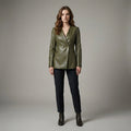 Woman wearing a green leather jacket and black pants on a gray background