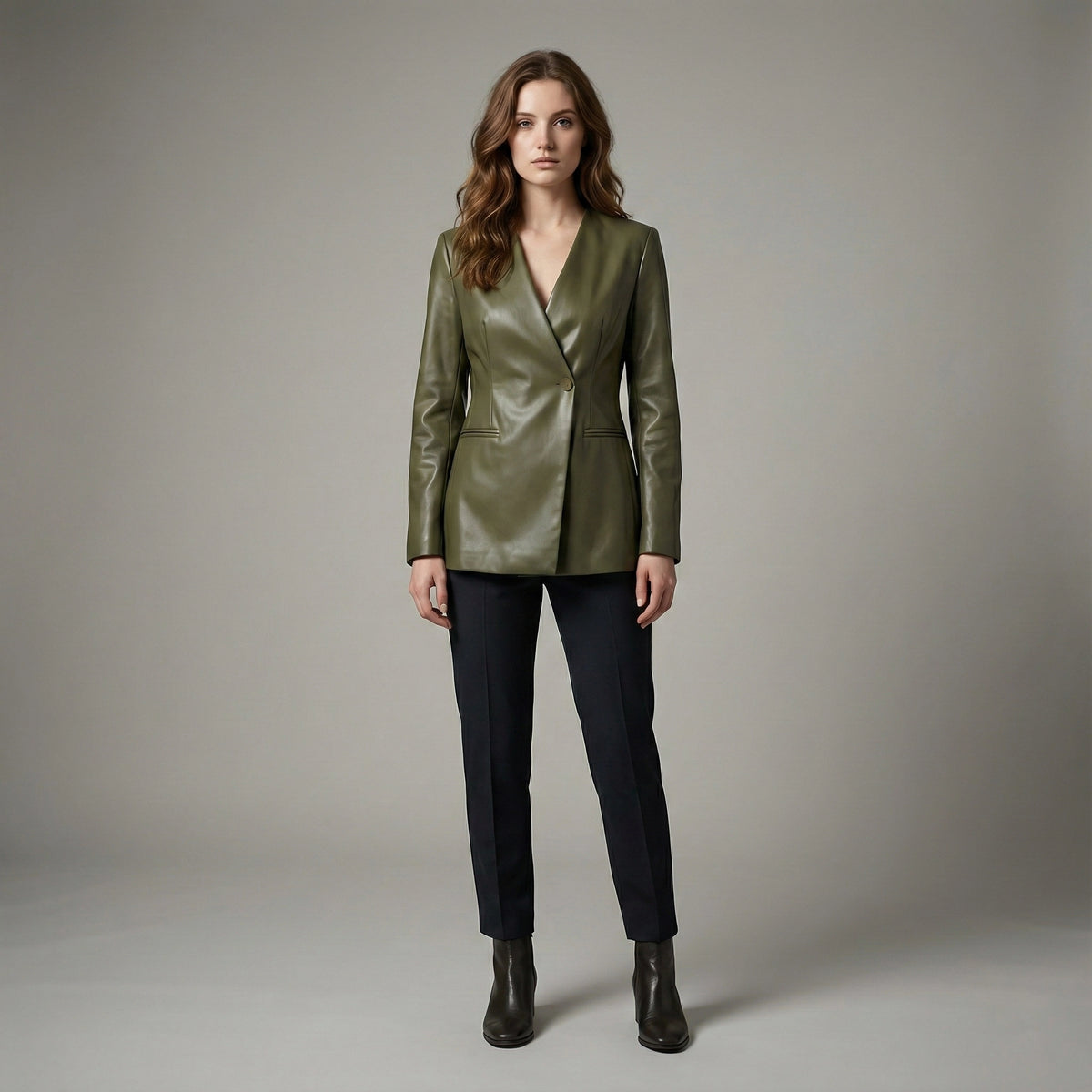 Woman wearing a green leather jacket and black pants on a gray background