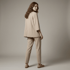 Woman wearing a beige suit standing against a plain background