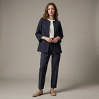 Woman wearing a navy suit with a white shirt against a beige background