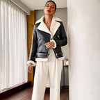 Woman wearing a black leather jacket with white fur trim in a room with white curtains.