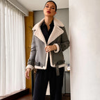 Woman wearing a gray coat with white fur trim in an indoor setting