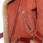 Close-up of a red suede jacket with fur lining and zipper detail on a white background